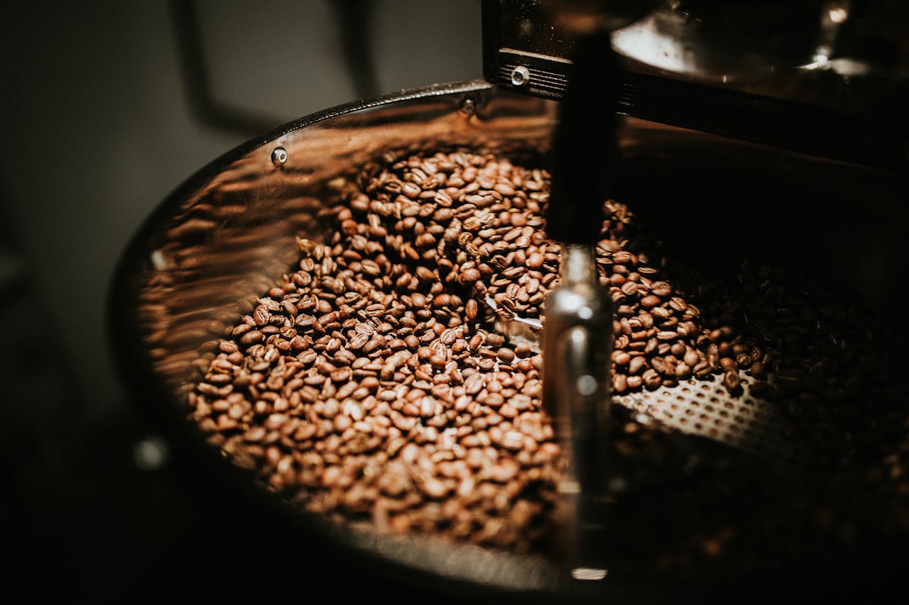 Services-01 Close-up of freshly roasted coffee beans in a large industrial coffee roaster, showcasing rich textures and warm tones.
